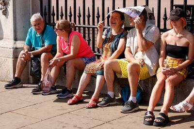 People sheltering from the sun outside Buckingham Palace in London on Monday: bright clothes advisable, maps as umbrellas less so. Reuters