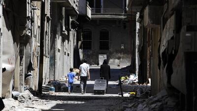 Members of a family walk past damaged buildings as they head to inspect their home in Homs. Omar Sanadiki/Reuters