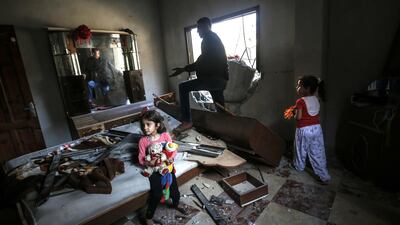 Young girls and a man gather among debris and shattered glass in a room that was hit during an Israeli air strike. AFP