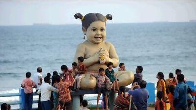 Tourists pose with a doll sculpture installed on a beach in Visakhapatnam, which is a popular tourist destination in south India. Deshakalyan Chowdhury / AFP