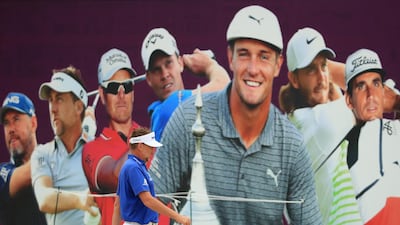 Ian Poulter of England walks past a tournament promotional poster of the Omega Dubai Desert Classic at Emirates Golf Club in Dubai. Getty Images
