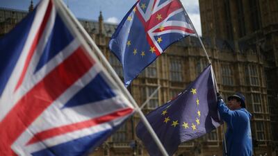 A pro-EU activist holds an EU and Union Jack flag outside of the Houses of Parliament in Westminster, central London on March 23, 2018. (AFP)