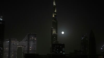 Rising behind the world's tallest tower, Burj Khalifa, in Dubai. AP