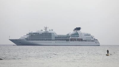 A woman paddles on a stand-up board near a cruise ship, close to the coastal city of Limassol, Cyprus. Reuters