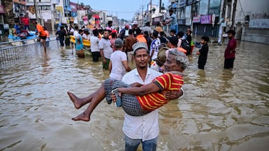 A youth carries an elderly man as they wade through a flooded street after heavy rainfall in Wellampitiya on the outskirts of Colombo, Sri Lanka. AFP