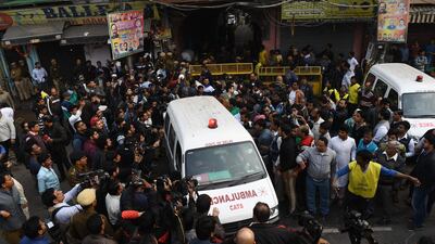 An ambulance is seen leaving sorrounded by media following a factory fire in Anaj Mandi area of New Delhi. At least 43 people have died in a factory fire in India's capital New Delhi, with the toll still expected to rise, AFP