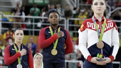 Gold medallist Simone Biles of the United States, centre, and silver medallist Aly Raisman of the US, left, sing their national anthem, as Bronze medallist Aliya Mustafina of Russia stands during the medal ceremony for the women’s gymnastics individual all-around at the 2016 Rio Olympics at Rio Olympic Arena on August 11, 2016 in Rio de Janeiro, Brazil. Dmitri Lovetsky / AP Photo