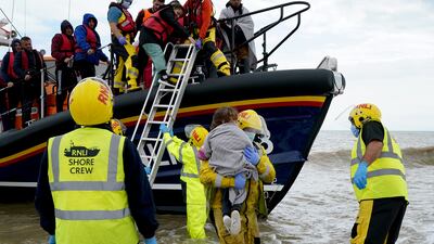 A young girl is carried to shore as migrants arrive in Dungeness, Kent, after being rescued from the English Channel by the RNLI on Thursday. PA