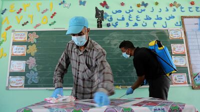 A Palestinian worker wearing a protective face mask cleans a table as another sanitises a classroom at a UN-run school before the start of new academic year, amid concerns about the spread of the coronavirus, in Gaza City. Reuters