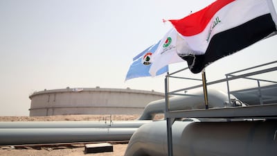 (FILES) A picture taken on May 31, 2015 shows Iraqi flags fluttering in front of a tank for oil at al-Fao (also spelled al-Faw) storage terminal, located on the al-Fao Peninsula, south of the Iraqi province of Basra. Iraq's prime minister said on August 21, 2026, that he wants to increase the country's oil exports to as much as 10 million barrels a day within six years. Before the Middle East war between Iran and the United States began, Iraq produced around four million barrels per day, and exported an average of 105 million barrels per month, mostly from its Basra oil terminal via Hormuz. The conflict has choked off the Strait of Hormuz. (Photo by HAIDAR MOHAMMED ALI / AFP)