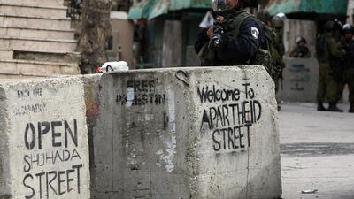 An Israeli soldier stands behind a graffiti-sprayed concrete block in Al-Shuhada Street in the West Bank town of Hebron during clashes last year with Palestinian protesters, who were demanding access to the street, which could only be used by Israeli ‘settlers’. ‘Settlers’ is one of the terms that the International Press Institute’s new handbook wants to remove from the journalistic lexicon. AFP / Hazem Bader