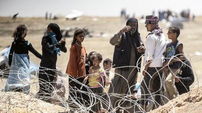 Syrian refugees gesture as they ask for water at the Turkish border near the Syrian town of Tal Abyad, on June 13. AFP PHOTO