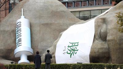 People look at a giant mock syringe for Covid-19 vaccines and a Chinese character meaning 'triumph' in the southeastern city of Daegu, South Korea. EPA