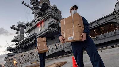 Sailors assigned to the aircraft carrier USS Theodore Roosevelt move ready to eat meals for sailors who have tested negative for Covid-19 and are being taken to local hotels in an effort to implement social distancing at Naval Base Guam. US Navy via AP