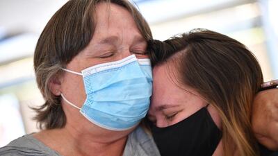 A woman embraces her daughter on her arrival from New Zealand at Sydney International Airport in New South Wales as Australia and New Zealand opened a trans-Tasman Sea quarantine-free travel bubble. AFP