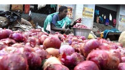 An Indian woman collects rotten onions thrown out of a wholesale market to sell them at a lower price. Nathan G / EPA