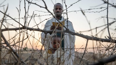 An Orthodox Christian Tigrayan refugee, who fled the conflict in the Ethiopia's Tigray region, reads prayers with his son in front of a church at the Hamdeyat Transition Center, near the Sudan-Ethiopia border, eastern Sudan. AP Photo