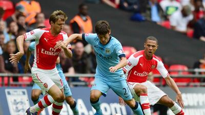 Manchester City’s Spanish midfielder David Silva, centre, runs with the ball between Arsenal’s Spanish defender Nacho Monreal, left, and Arsenal’s English defender Kieran Gibbs, right, during the Community Shield trophy after Arsenal won the FA Community Shield football match between Arsenal and Manchester City at Wembley Stadium in north London on August 10, 2014. AFP PHOTO / CARL COURT