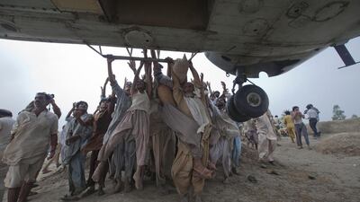 Marooned flood victims try to grab the side bars of a hovering army helicopter distributing food supplies in the Muzaffargarh district of Punjab province, Pakistan, in August 2010. Adrees Latif