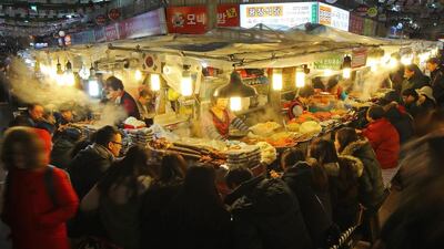 Steam from cooking pots filling the air at the food stalls of the Kwangjang Market in downtown Seoul, South Korea, as locals seek comfort from the wintry weather in the evening. Snow began falling across the country late in the day. EPA / Yonhap