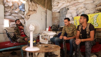 Moawiya Sayasina sits with his comrades in a position fortified with sandbags near the frontline in a rebel-held neighbourhood in the southern Syrian city of Daraa. Mohamad Abazeed / AFP