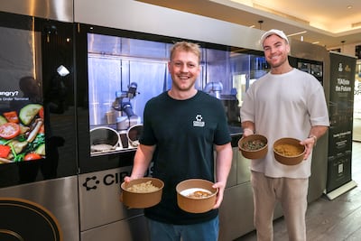 (L-R) Dylan Frayne and Michael Bassler with the CA-1, a fully autonomous, AI-powered robotic kitchen and meal-production system. Photo: Victor Besa / The National