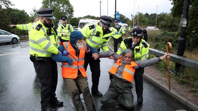 Police officers detain Insulate Britain activists. Reuters