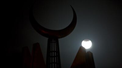 The partially-eclipsed moon rises against a crescent mounted on Faisal Mosque in Islamabad, Pakistan. B.K. Bangash / AP Photo.