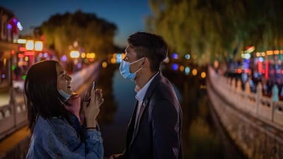 A couple share a laugh as they take pictures with a phone on a bridge at the Hu Hai lake in Beijing, China. AFP