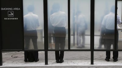 People smoke cigarettes at a smoking booth on a street in Tokyo. Issei Kato / Reuters