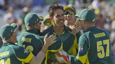 Mitchell Johnson, centre, receives congratulations from teammates after taking the wicket of England’s Eoin Morgan. Tony Ashby / AFP