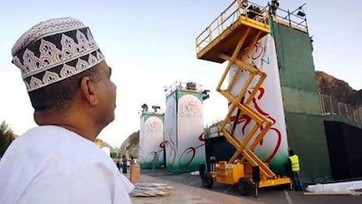 A man watches workers prepare for the opening ceremony of the Tour of Oman cycling race, in Muscat, Oman, Friday, Feb. 12, 2010. The race will take place over six days, From Feb. 14 to Feb. 19, 2010. (AP Photo/Christophe Ena)