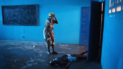 Umu Fambulle stands over her husband Ibrahim after he staggered and fell, knocking him unconscious in an Ebola ward on August 15 in Monrovia, Liberia. People suspected of contracting the Ebola virus are being sent by Liberian health workers to the centre, a closed primary school originally built by USAID. John Moore / Getty Images