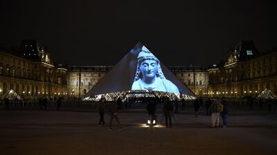 Images of the art displayed in the Louvre Abu Dhabi are projected onto the Louvre Pyramid in Paris Wednesday night to mark the opening of the museum on Saadiyat island. Eric Feferberg / AFP