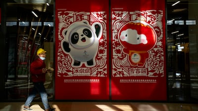 A worker walks past posters showing the Olympic mascot Bing Dwen Dwen and Paralympic mascot Shuey Rhon Rhon at the Winter Olympic Village in Beijing. AP