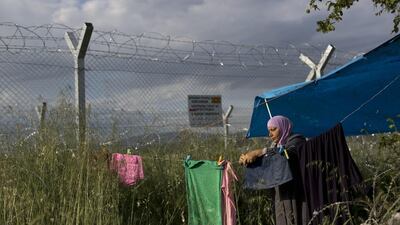 A woman hangs laundry near her tent in front of the wired fence that separates Greece and Macedonia at a makeshift refugee camp on the northern Greek border point of Idomeni. Thousands of stranded refugees and migrants have camped in Idomeni for months after the border was closed. Petros Giannakouris / AP Photo