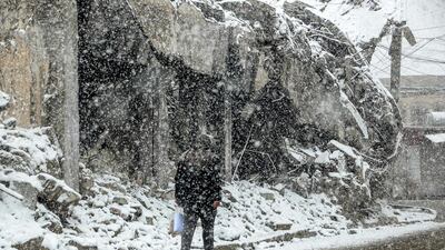 A man walks through a snow blizzard past heavily damaged buildings in Mosul, northern Iraq. AFP
