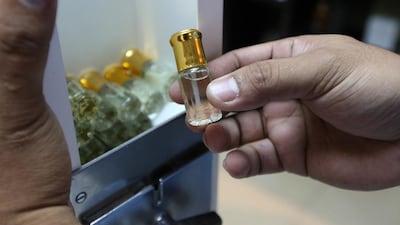 SA worker at Sahar Al Sharq Perfumes in Sharjah shows how to refill one of the perfume vending machines that can be found dispensing scents to worshippers outside mosques in the UAE. Pawan Singh / The National