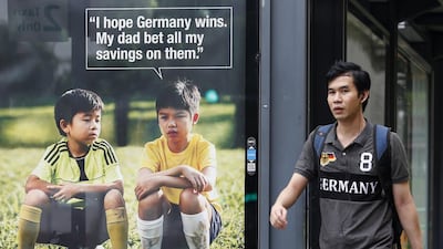 A man walks past a World Cup anti-gambling advertisement at a taxi stand in Singapore on July 9, 2014. Singapore has scored an own goal with the World Cup anti-gambling ad which features a crestfallen boy telling his friends his dad bet his life savings on Germany, who reached the finals by thrashing host nation Brazil 7-1. REUTERS/Edgar Su