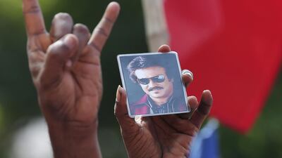 A picture of actor Rajinikanth is shown by a supporter as they celebrate the launch of his political party. Ravikumar / Reuters