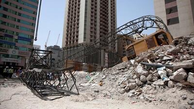 Construction workers work away to clean up remains of a crane that collapsed earlier that morning on Tuesday, July 12, 2011, during the morning rush hour in downtown Abu Dhabi. No one was hurt and only road blocks and the crane itself suffered damages. (Silvia Razgova/The National)