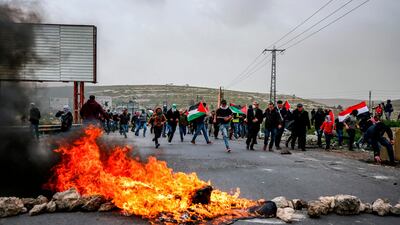 Men wave the Palestinian national flag during clashes with Israeli forces following Land Day protests. AFP