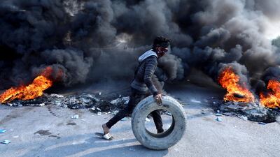 A protester pushes a tyre next to burning tyres during ongoing anti-government protests in Kerbala, Iraq. Reuters