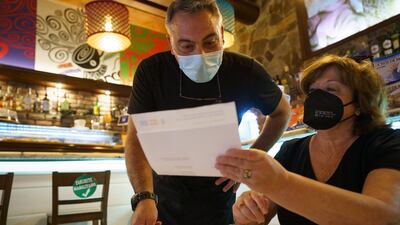 A bar worker looks at the EU Covid certificate of a customer in Santa Cruz de Tenerife, in the Canary Islands, Spain, on July 26. EPA