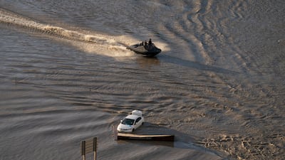 A boat speeds along a flooded motorway.