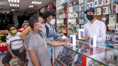 Staff and customers with face masks at a mobile phone shop at Mussafah 32. Victor Besa / The National