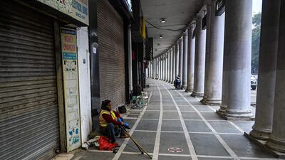 A New Delhi Municipal Corporation worker sits in front of closed shops.
