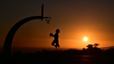 A boy shoots hoops at sunset on August 19, 2025 in San Pedro, California. The National Weather Service issued an extreme heat warning for parts of Los Angeles County which will be in effect from August 21 into the weekend, with temperatures expected to reach 110 degrees in some areas. (Photo by Frederic J. BROWN / AFP)