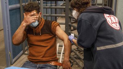 A Palestinian labourer covers his eyes as he receives a dose of the Moderna Covid-19 vaccine at a temporary vaccination centre at the Meitar checkpoint crossing into Israel, south of Hebron, West Bank. Bloomberg