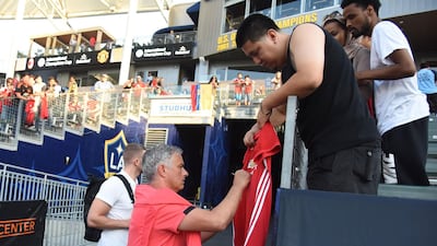 Manchester United's coach Jose Mourinho signs an autograph before the start of the match. AFP
